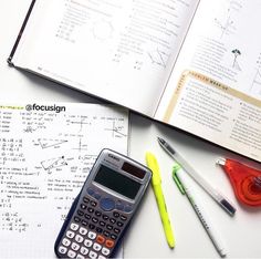 a calculator sitting on top of a book next to some pens and markers