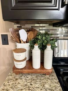 kitchen utensils are sitting on a wooden tray in front of the stove top