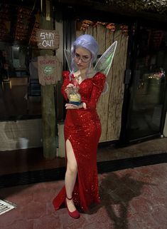 a woman dressed as tinkerbell holding an award in front of a storefront