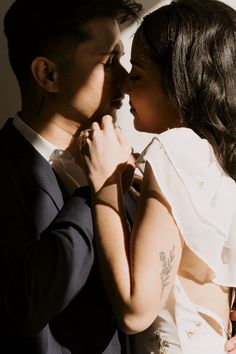 a man in a suit and tie kissing a woman's face with her arm around him