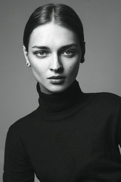 a black and white photo of a woman wearing a turtle neck sweater with her hands on her hips