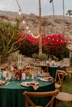 a table set up with green cloths and place settings for an outdoor dinner in the desert