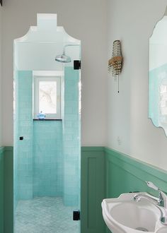 a bathroom with blue and green tiles on the walls, along with a white sink