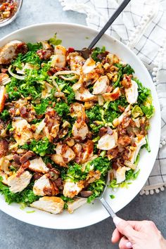 a white bowl filled with chicken, lettuce and bacon on top of a table