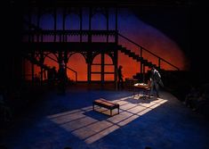 the stage is lit up with people sitting in chairs and one person standing on a bench