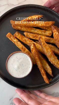 crispy garlic parmesan fries on a black plate with ranch dip in the middle