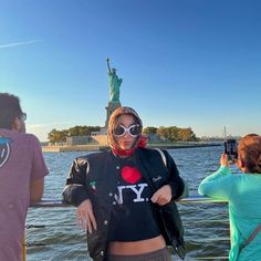 a woman taking a selfie with the statue of liberty in the background