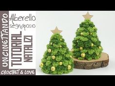 two small crocheted christmas trees sitting on top of a piece of wooden logs