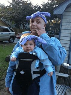 a man holding a child in his arms while he is wearing a blue coat and hat