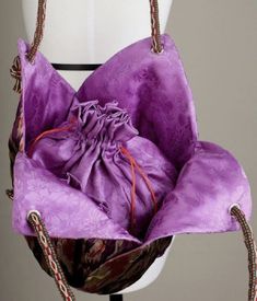 a purple handbag sitting on top of a white mannequin's head