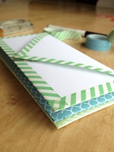 an open envelope sitting on top of a wooden table next to tape and some scissors