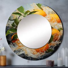 a round mirror with oranges and leaves on the surface next to a vase filled with flowers