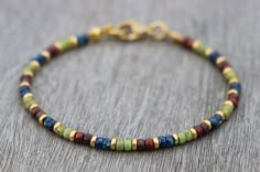 Friendship bracelet, colorful beaded with tiny Miyuki seed beads in beautiful red, green and blue. These glass beads have a picasso coating; each bead is unique! The gold colored spacers make the colors stand out even more! It also ensures a dainty touch. You can wear this thin bohemian bracelet on its own, for a minimalist look, or you can stack it with other boho bracelets. It will give a beautiful multi color accent to your outfit. Great for those special moments, or spoil yourself and make i Simple Bracelets Diy Beads, Seed Bead Color Combinations, Bead Bracelets Ideas, Bracelet Homemade, Tiny Bead Bracelet, Homemade Bracelets, Stone Bead Jewelry, Colorful Bracelet, Miyuki Bracelet