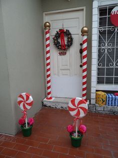 two candy canes in front of a door decorated for christmas with wreath and decorations