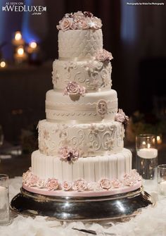 a white wedding cake with pink flowers on the top and bottom tier is sitting on a silver platter