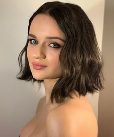 a close up of a person wearing a bra and posing for the camera with her hair pulled back