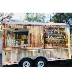 a food truck is parked on the side of the road in front of some trees