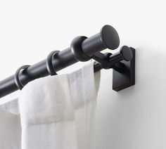 the curtain rod is attached to the side of a white wall with black metal hardware