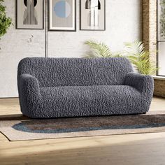 a gray couch sitting on top of a wooden floor next to a potted plant