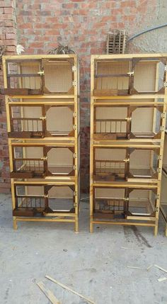 two wooden shelves filled with bird cages next to each other on the ground in front of a brick wall