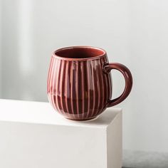 a brown mug sitting on top of a white block