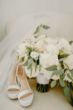 a bridal bouquet and bride's shoes on a couch