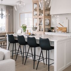 a kitchen with white counter tops and black chairs