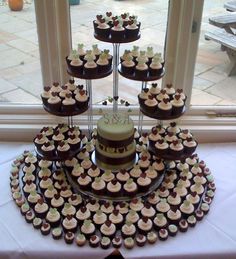 a cake and cupcakes are arranged on a table in front of a window