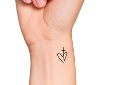 a woman's arm with a cross and heart tattoo on the left side of her wrist