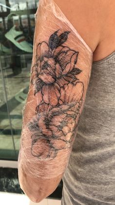 a woman's arm with flowers on it and the back of her arm is covered in black ink