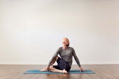 a man sitting on a yoga mat in the middle of a room with his legs crossed