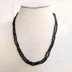 This vintage Bohemian necklace is a stunning piece featuring an abundance of black seed beads, intricately strung together to create a long, flowing design. The necklace embodies the essence of boho-chic style, with its effortless, earthy elegance and free-spirited vibe. The deep black beads give it a versatile quality, allowing it to be paired with a variety of outfits, from casual to more formal ensembles. Its generous length provides multiple styling options--you can wear it long for a laid-back look or double it up for added texture and visual interest. The craftsmanship and intricate beadwork reflect a vintage charm that appeals to those who appreciate unique, handcrafted jewelry. Whether layered with other pieces or worn alone as a statement accessory, this Bohemian necklace is a tim Black Double Strand Necklace With Beads, Black Double Strand Necklace With Black Beads, Black Beaded Long Necklace With Round Beads, Black Beaded Necklace With Round Beads, Black Long Necklace With Round Beads, Black Double Strand Beaded Necklaces For Jewelry Making, Black Long Beaded Necklace With Faceted Beads, Black Faceted Beads Long Necklace, Black Long Faceted Beaded Necklace