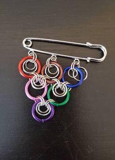 "∙ Simple yet elegant, this brooch consists of silver metal rings in various sizes flanked by 15 mm anodized color rings. ∙ This particular design can be worn from either side, since the rings are not fixed.  ∙ Kilt pin has a silver finish. ∙ Finished size: 2.25\" across x 2.50\" width (top to bottom) Your brooch will arrive in a kraft gift box with contrasting raffia ribbon. Gift boxes are 100% recycled cardboard boxes (made with 77% post-consumer fiber and 23% pre-consumer fiber). Boxes are ma Kilt Pin Brooches, Raffia Ribbon, Color Rings, Ribbon Gift, Shawl Pin, Kilt Pin, Recycled Cardboard, Kraft Gift Boxes, Shawl Pins