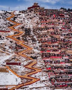 a very long road going up the side of a mountain covered in snow and buildings