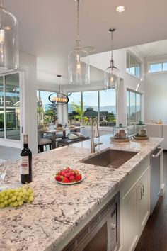 a kitchen with marble counter tops and an island in front of the window overlooking the ocean