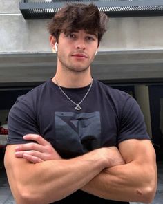 a man with his arms crossed standing in front of a building