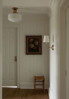 a hallway with white walls and wood flooring next to a painting on the wall