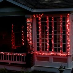 a house with christmas lights on the front porch and side windows, all lit up in red