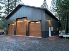 two garages with lights on each side of them in front of some pine trees