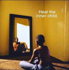 a boy sitting in front of a mirror with his reflection on the wall next to him