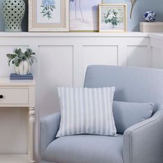 a blue chair sitting next to a white table with pictures on the wall above it