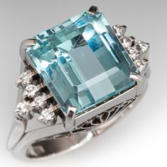 This gorgeous vintage ring is centered with one (1) emerald cut aquamarine that is set into a four-prong setting. On either side of the aquamarine are five (5) round brilliant cut diamonds that are prong set. The side galleries of the ring have ornate filigree designs. The ring measures 12.1mm at the top, rises 10.6mm above the finger, tapering to 2.9mm wide and 1.6mm thick at the base of the shank. It is currently a size 6 with a knife edge shank. Elegant Gia Certified Aquamarine Rings, Aquamarine Emerald-cut Diamond Jewelry, Luxury Aquamarine Brilliant Cut Jewelry, Blue Emerald-cut Aquamarine Diamond Ring, Aquamarine Stone Ring, Emerald Cut Aquamarine Ring, Luxury Aquamarine Emerald-cut Rings, Aquamarine Cocktail Ring, Aquamarine Ring Vintage