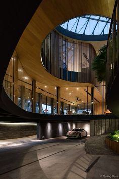 a car is parked in front of a circular building with glass and wood windows at night