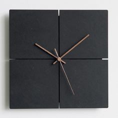 a square clock made out of black tiles with wooden sticks sticking out of the middle