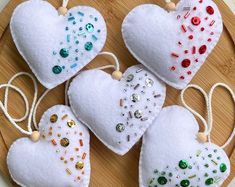 four white heart ornaments are on a wooden platter with string and beadwork