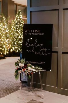 a welcome sign sitting on top of a white tiled floor next to a christmas tree