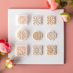 some cookies are sitting on a white tray next to pink flowers and two red roses