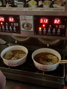 two bowls of food sitting on top of a stove in front of a menu board