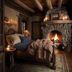 a bedroom with a stone fireplace and bed in the corner, lit by candles on either side