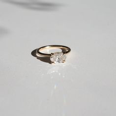 a diamond ring sitting on top of a white surface with the sun shining through it